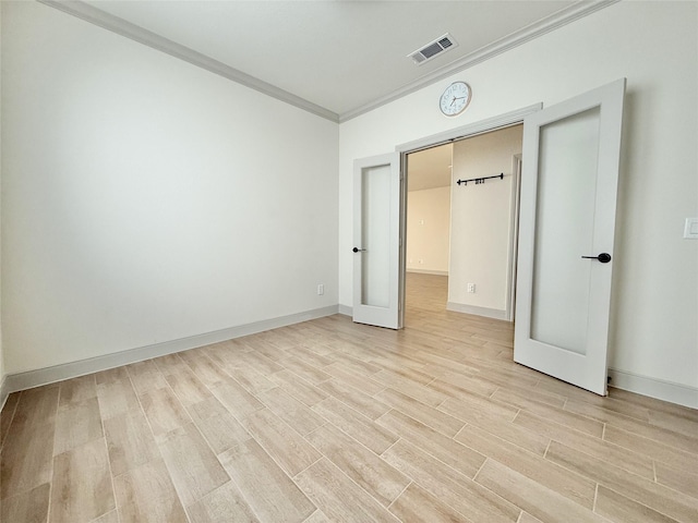 unfurnished bedroom featuring light wood-style flooring, baseboards, visible vents, and ornamental molding