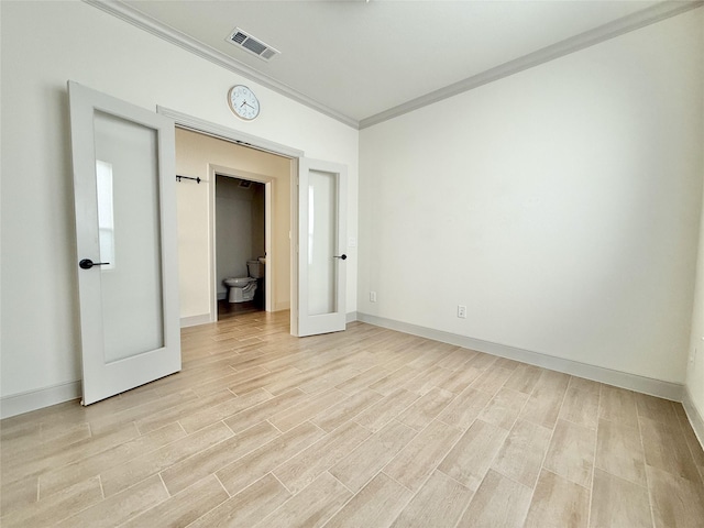 spare room with crown molding, baseboards, visible vents, and light wood-type flooring