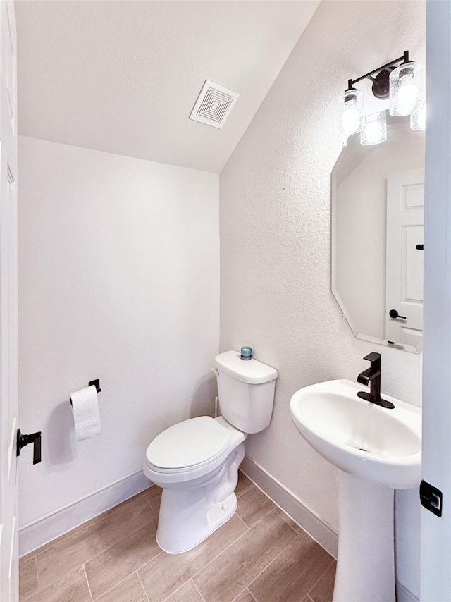 bathroom featuring toilet, baseboards, visible vents, and wood finish floors