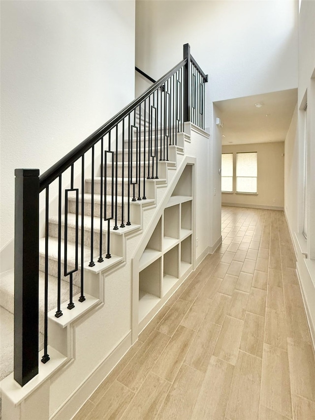 stairs with a high ceiling, baseboards, and wood finished floors