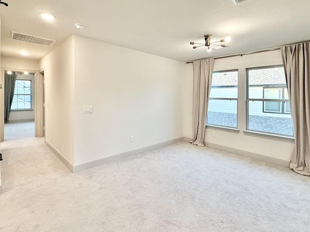 spare room featuring light carpet, visible vents, and baseboards