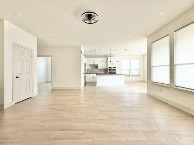 unfurnished living room with light wood finished floors and baseboards