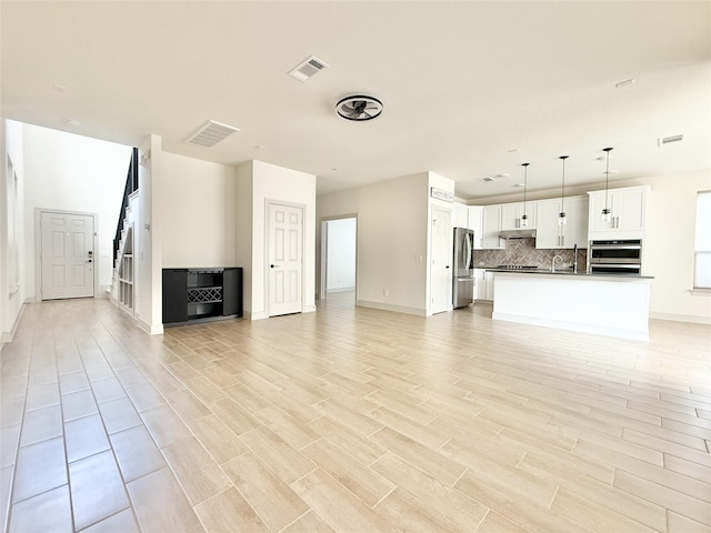 unfurnished living room featuring visible vents and light wood-style flooring