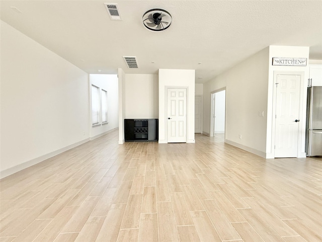 unfurnished living room with visible vents, baseboards, and light wood finished floors