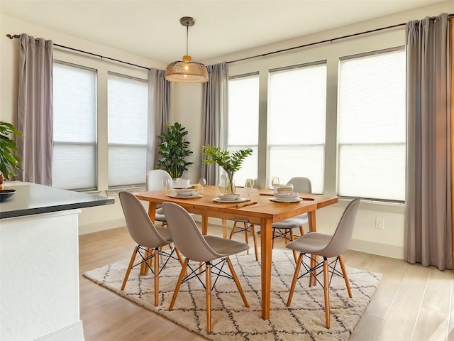 dining space with baseboards and light wood finished floors