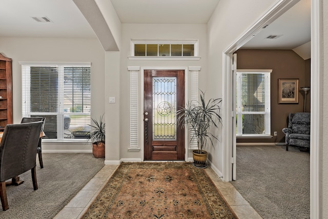 carpeted entrance foyer featuring tile patterned floors, baseboards, and visible vents