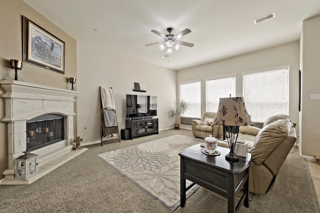 carpeted living area with visible vents, baseboards, ceiling fan, and a glass covered fireplace