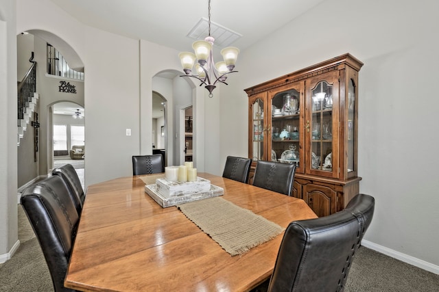 carpeted dining space with baseboards, arched walkways, and an inviting chandelier