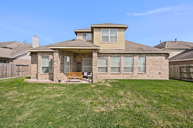 back of property featuring brick siding, a fenced backyard, a yard, and a patio