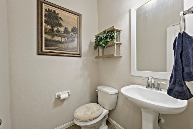 bathroom featuring toilet, baseboards, and a sink