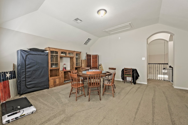 dining room with visible vents, light carpet, attic access, and vaulted ceiling