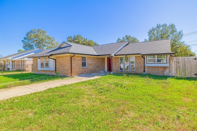 single story home featuring brick siding, a shingled roof, a front yard, and fence