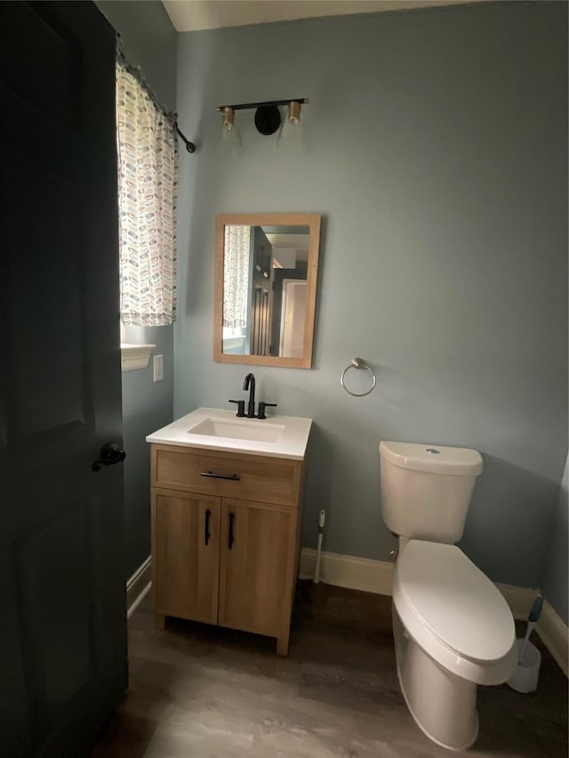 full bath with baseboards, toilet, a shower with shower curtain, wood finished floors, and vanity