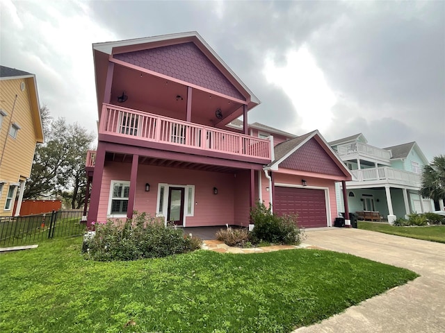 view of front of house featuring fence, concrete driveway, an attached garage, a front yard, and a balcony