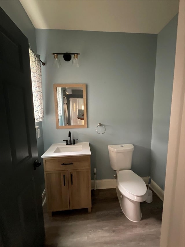 full bathroom featuring baseboards, toilet, wood finished floors, and vanity