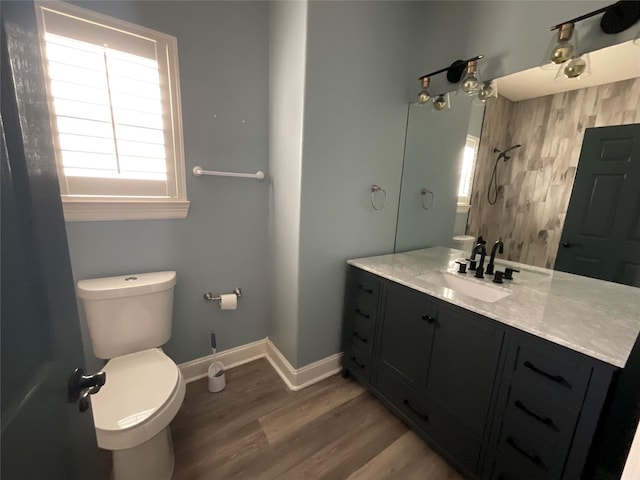 bathroom with vanity, wood finished floors, baseboards, a shower, and toilet