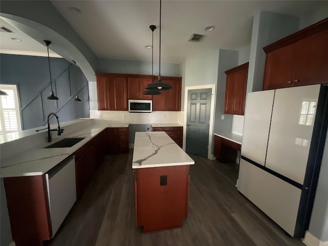 kitchen with visible vents, dark wood-type flooring, a sink, stainless steel microwave, and freestanding refrigerator