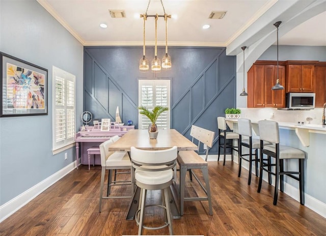 dining area with crown molding, dark wood-style floors, and visible vents