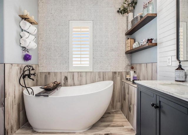 bathroom with a freestanding tub, tile walls, and vanity