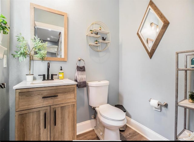 bathroom with baseboards, toilet, wood finished floors, and vanity