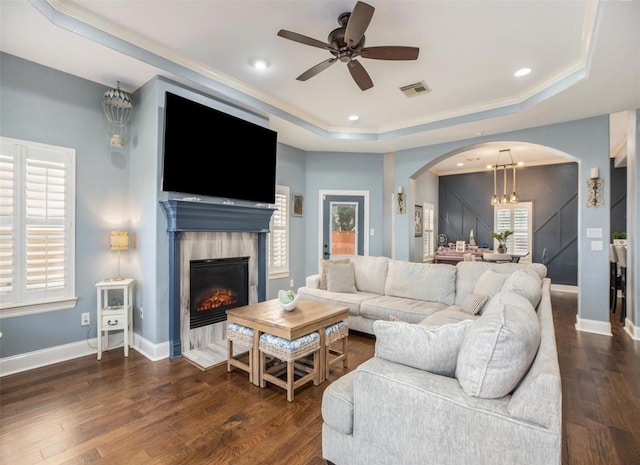 living room featuring a raised ceiling, wood finished floors, visible vents, and a healthy amount of sunlight