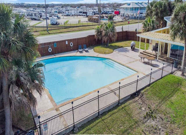 community pool with a patio area, a yard, and fence