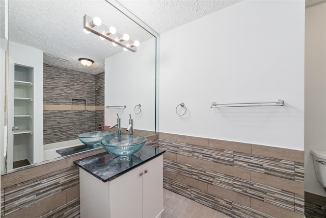 16123 Ridgegreen Dr, Houston, TX 77082 - bathroom featuring vanity, a tile shower, a textured ceiling, tile walls, and toilet