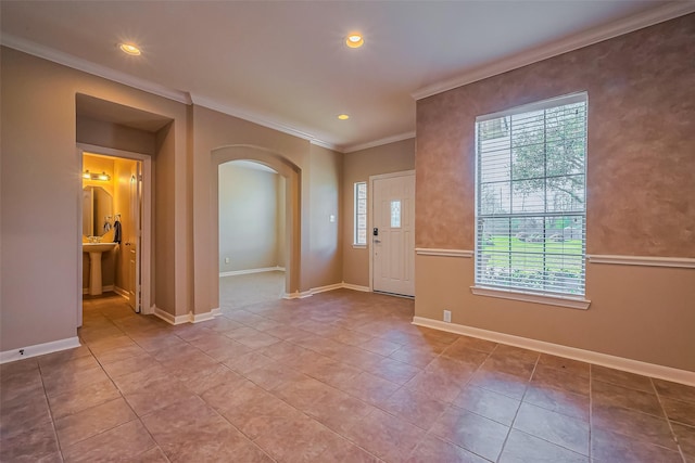foyer entrance with arched walkways, crown molding, recessed lighting, tile patterned floors, and baseboards