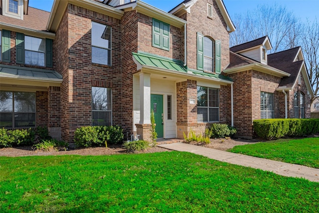 view of front of property with brick siding, a front lawn, and a standing seam roof