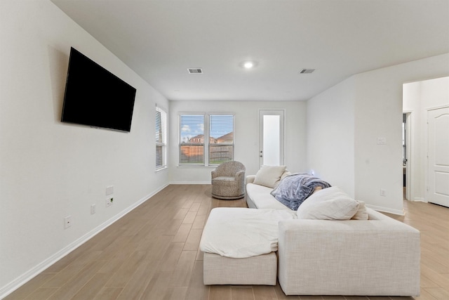 living area with visible vents, light wood-type flooring, and baseboards