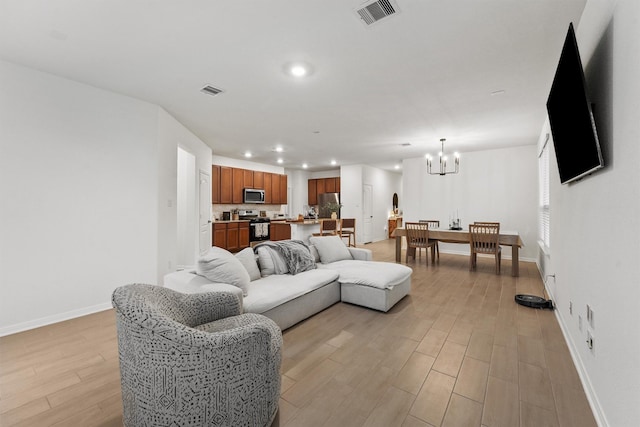 living area featuring visible vents, baseboards, recessed lighting, light wood-style floors, and a notable chandelier