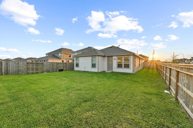 rear view of property with a lawn and a fenced backyard