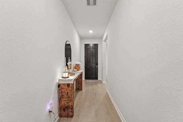 corridor with visible vents, baseboards, and light wood finished floors