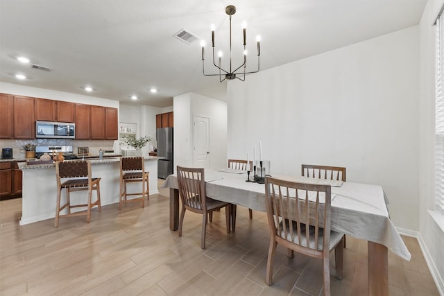 dining area with visible vents, recessed lighting, light wood-style floors, and an inviting chandelier