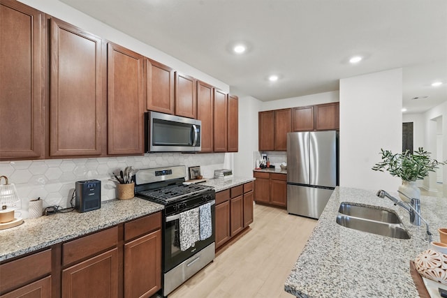 kitchen with light wood-style flooring, recessed lighting, a sink, decorative backsplash, and stainless steel appliances