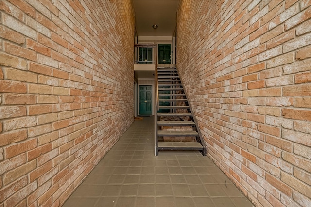 stairs featuring brick wall and tile patterned flooring