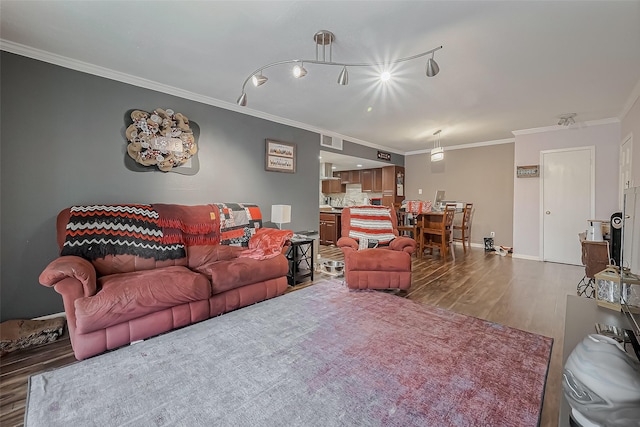 living room with visible vents, baseboards, wood finished floors, and crown molding