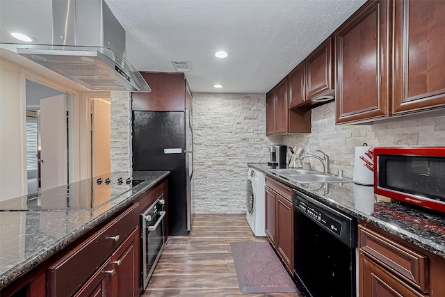 kitchen featuring visible vents, black appliances, island exhaust hood, washer / clothes dryer, and a sink