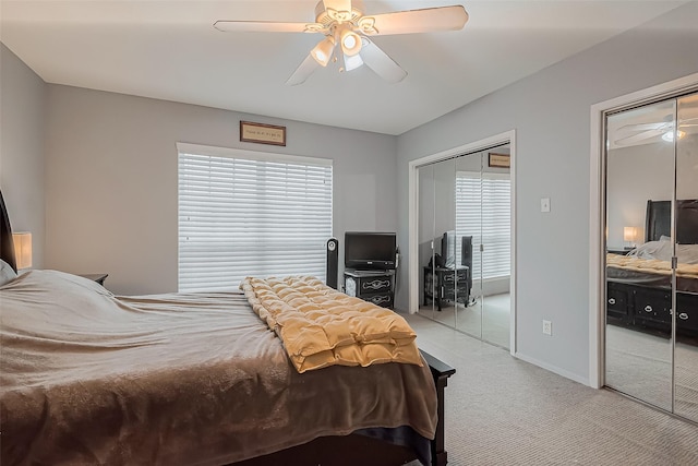 carpeted bedroom featuring baseboards, two closets, and a ceiling fan