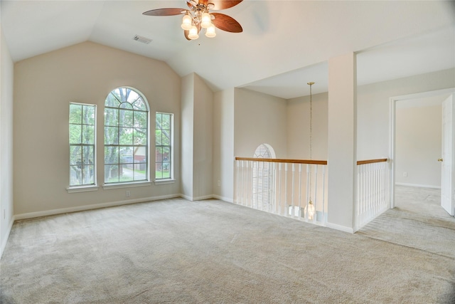 carpeted spare room with lofted ceiling, baseboards, a ceiling fan, and visible vents
