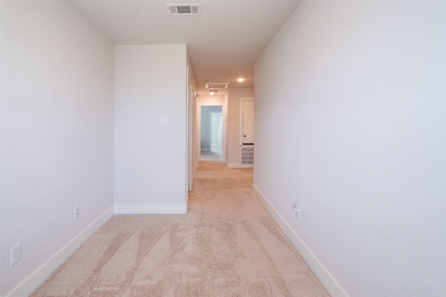 hallway featuring visible vents, light colored carpet, and baseboards