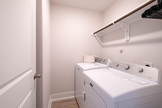 laundry area with washer and clothes dryer, laundry area, baseboards, and wood finished floors