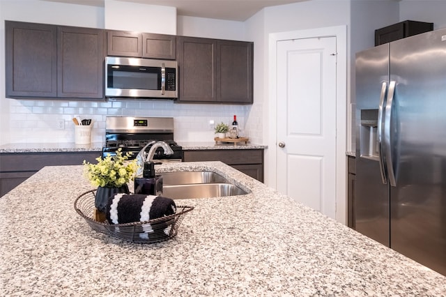 kitchen with decorative backsplash, dark brown cabinetry, a sink, and stainless steel appliances