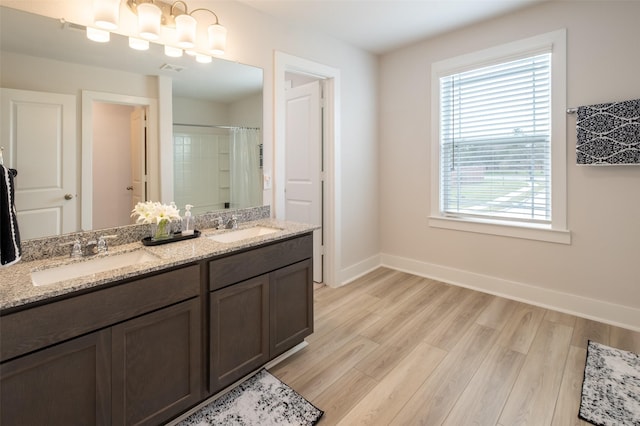 full bath with a sink, baseboards, and wood finished floors