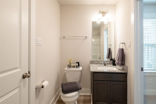 full bathroom with baseboards, toilet, vanity, and walk in shower