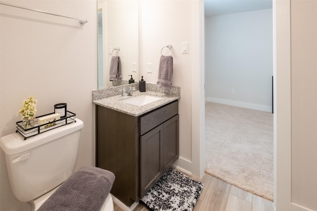 bathroom featuring vanity, toilet, wood finished floors, and baseboards