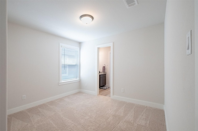 spare room featuring visible vents, light colored carpet, and baseboards