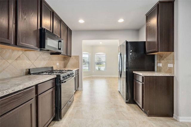 kitchen with dark brown cabinetry, gas range oven, black microwave, and light countertops