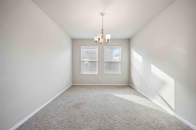 carpeted empty room with a notable chandelier and baseboards