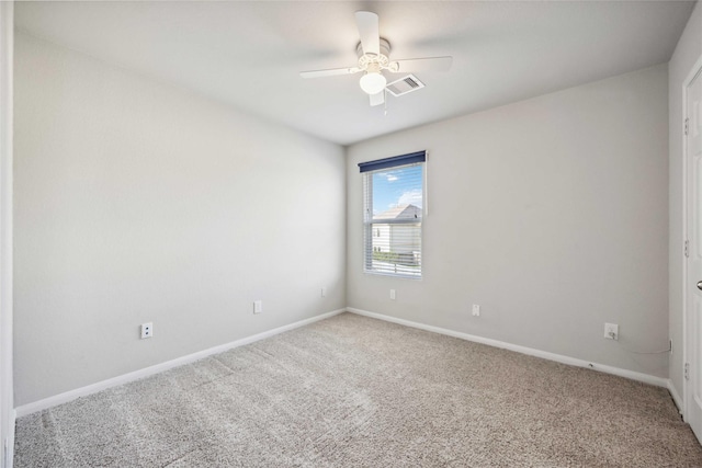 carpeted spare room with visible vents, baseboards, and ceiling fan